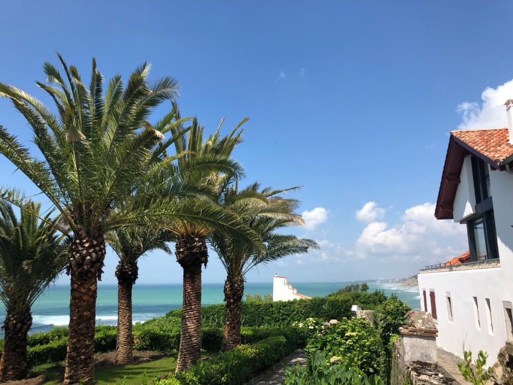 a row of palm trees in front of a building at Appartement Parlementia, Phare de Koskenia in Guéthary