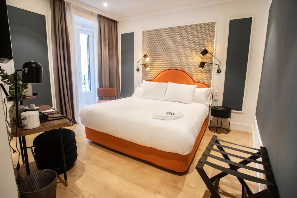 um quarto de hotel com uma cama grande com lençóis brancos em Soho Boutique Opera em Madrid