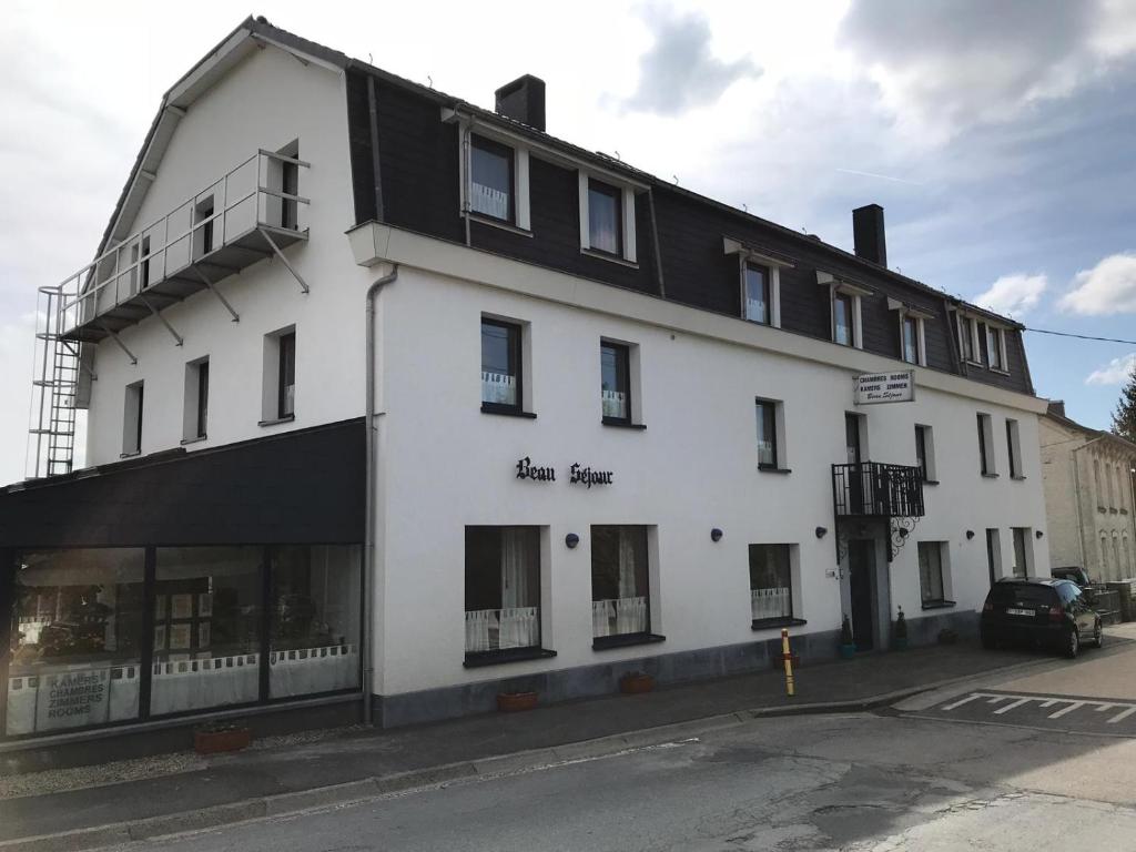 a white building with a black roof on a street at Beau-sejour in Francorchamps