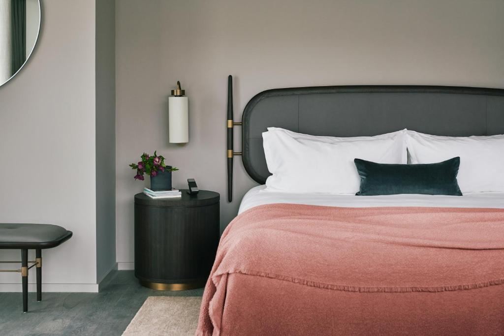 1 dormitorio con 1 cama con manta roja y mesa en The Stratford Hotel London en Londres