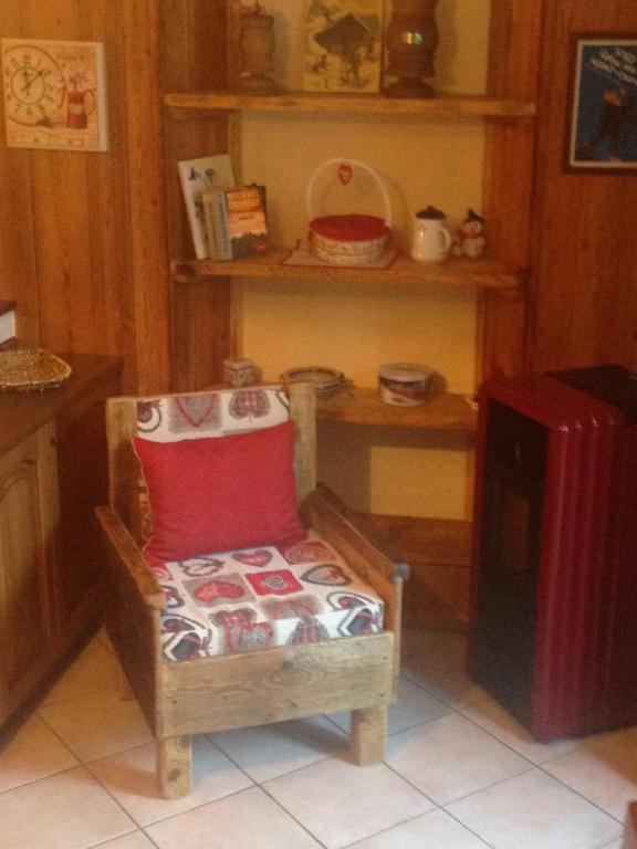 a room with a chair with a red pillow and a refrigerator at MAISON CESAR in Cogne
