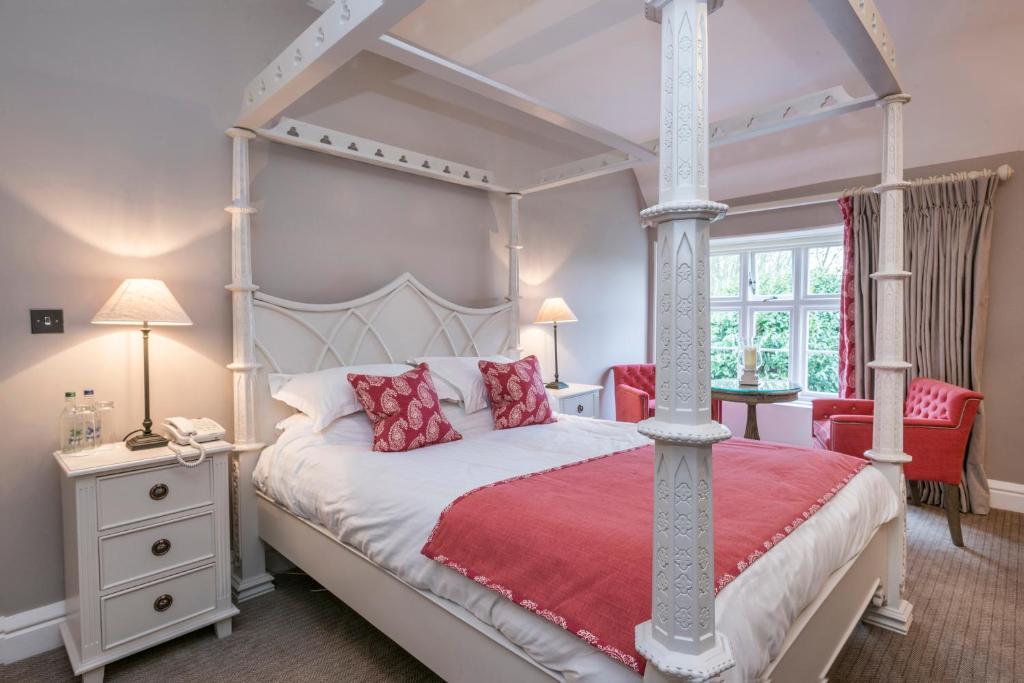 a bedroom with a four poster bed with red pillows at Heacham Manor Hotel in Hunstanton