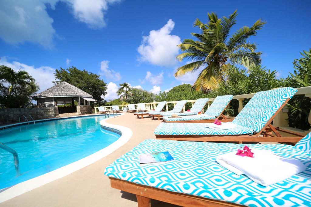 a group of lounge chairs next to a swimming pool at The Great House in Saint Peter