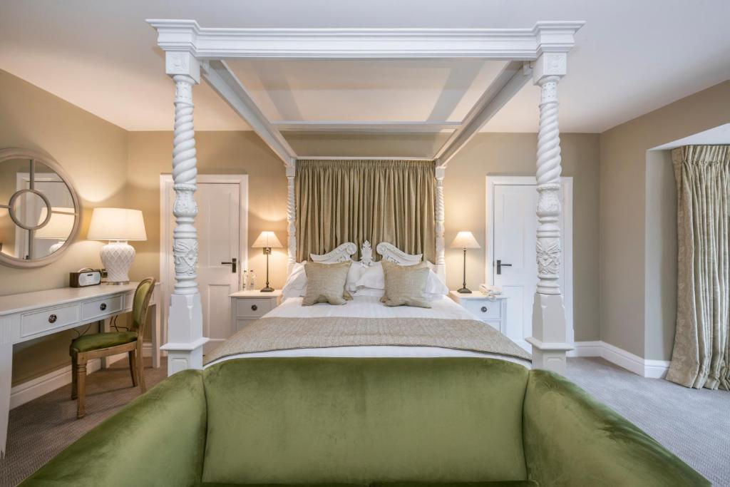 a bedroom with a large bed with white columns at Heacham Manor Hotel in Hunstanton
