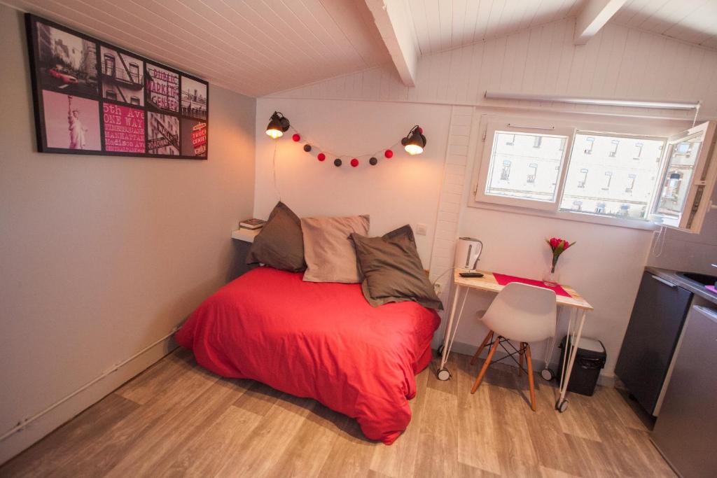 a small bedroom with a red bed and a desk at Capitole - Studio d&#39;amoureux sur les toits in Toulouse