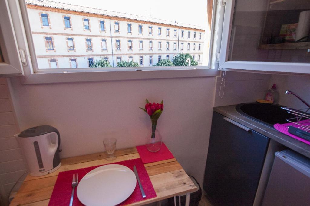 a small kitchen with a table and a window at Capitole - Studio d&#39;amoureux sur les toits in Toulouse