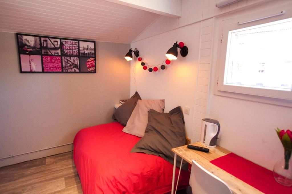 a bedroom with a red bed and a desk at Capitole - Studio d&#39;amoureux sur les toits in Toulouse