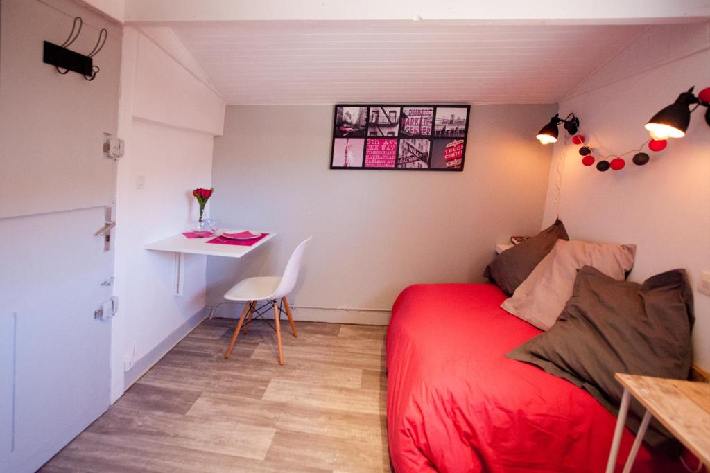 a bedroom with a red bed and a desk at Capitole - Studio d&#39;amoureux sur les toits in Toulouse