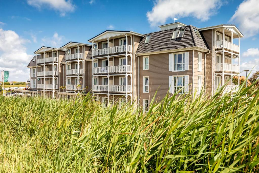 a large building on the beach with tall grass at Hotel Zweite Heimat in Sankt Peter-Ording