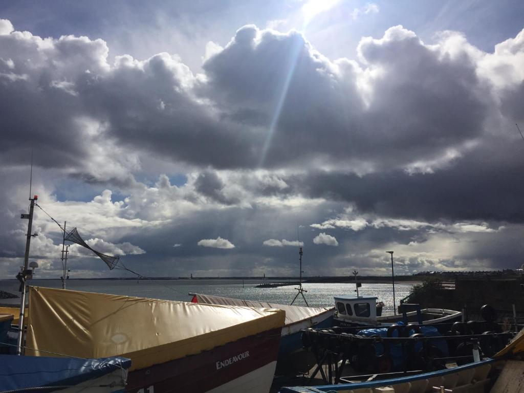 a group of boats on the water under a cloudy sky at The Mules in Newbiggin-by-the-Sea