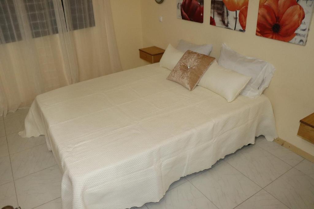 Bett mit weißer Bettwäsche und Kissen in einem Zimmer in der Unterkunft Apartamento Preguiça in Espargos