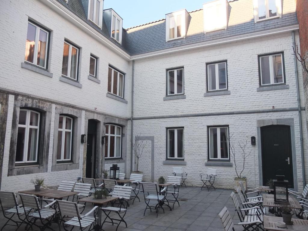 une cour avec des tables et des chaises devant un bâtiment dans l'établissement Boutique Hotel Grote Gracht, à Maastricht