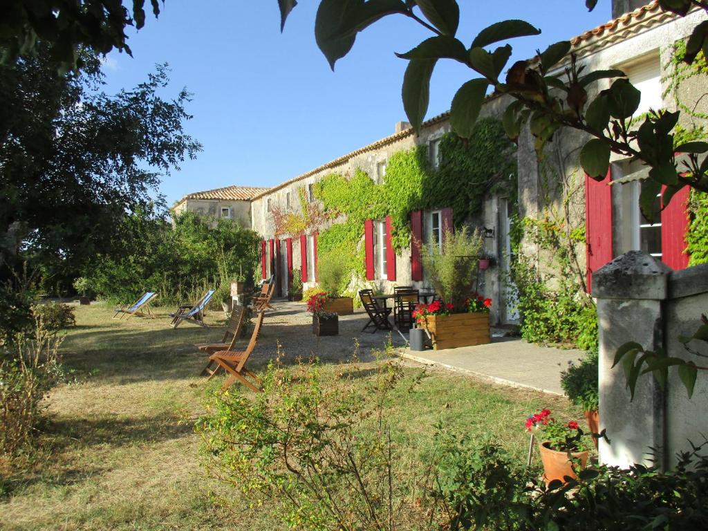 ein Haus mit roten Türen und einem Garten mit Stühlen in der Unterkunft Logis de Bois Roche (2) in Saint-Bonnet-sur-Gironde