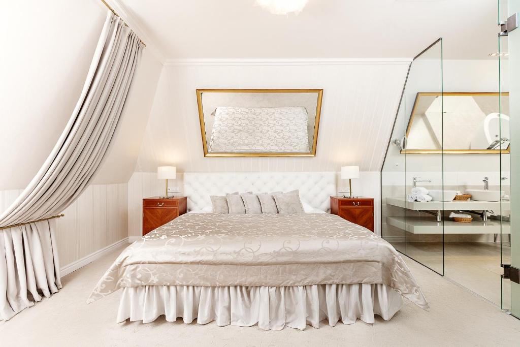 a white bedroom with a bed and a mirror at Hotel Hoffmeister in Prague