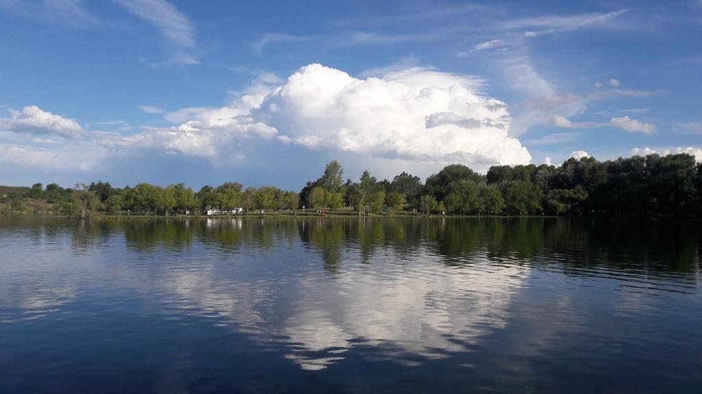 un gran cuerpo de agua con árboles y un cielo nublado en Cabaña Trapiche San Luis en Trapiche