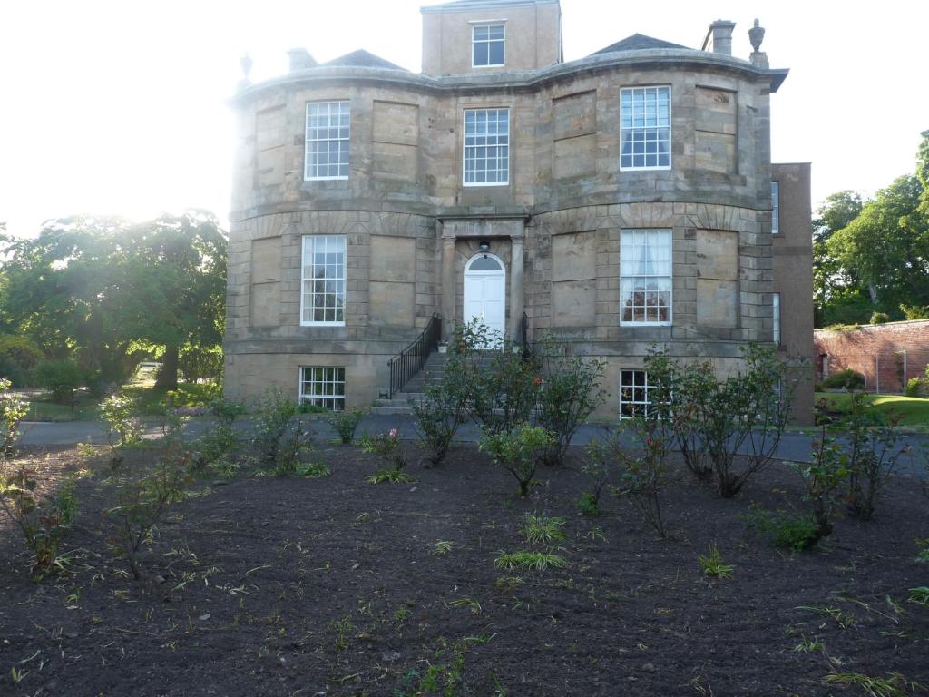 an old stone house with trees in front of it at Kirkmay House in Crail