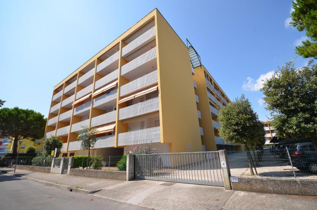a yellow building with a fence in front of it at Appartamenti Atlante in Bibione