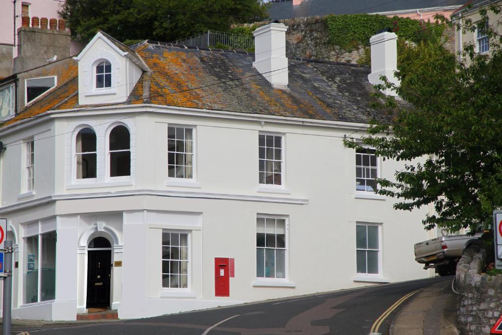 a white house with a red door on a street at The Old Post Office in Salcombe