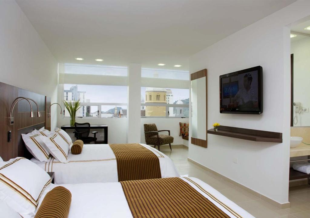 Habitación de hotel con 2 camas y TV de pantalla plana. en San Simon Hotel Pereira, en Pereira