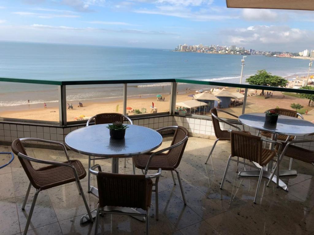 2 mesas y sillas en un balcón con vistas a la playa en Amplo apartamento em Guarapari com vistas pro mar, en Guarapari