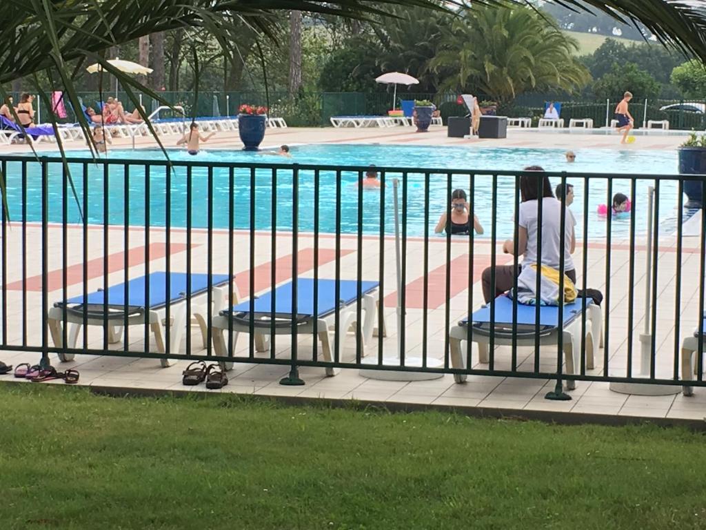 a woman sitting on a chair in front of a swimming pool at Domaine de Bordaberry in Urrugne