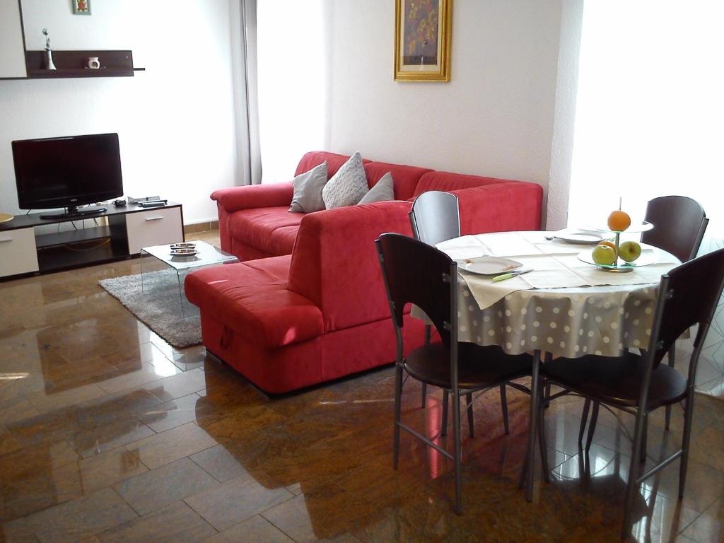 a living room with a red couch and a table at Apartment Oaza in Rovinj