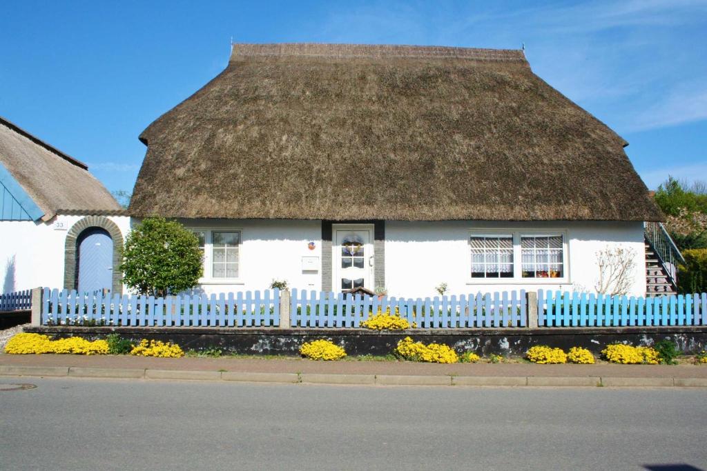 a thatch roof house with a white fence and flowers at Komfortfewo Steuerrad in Kasnevitz