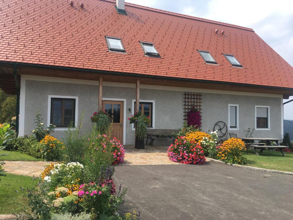 uma casa com um banco e flores em frente em Hopfenhof em Leutschach