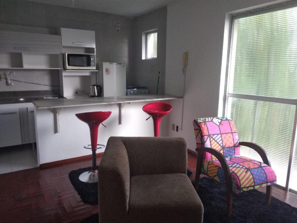 uma sala de estar com uma cadeira e uma cozinha em Apart. hotel Vitrine em Bagé