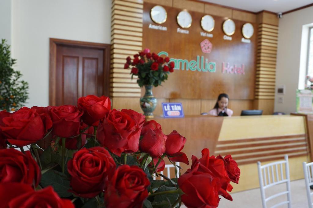 a vase of red roses sitting in front of a desk at Camellia Hotel in Thanh Hóa