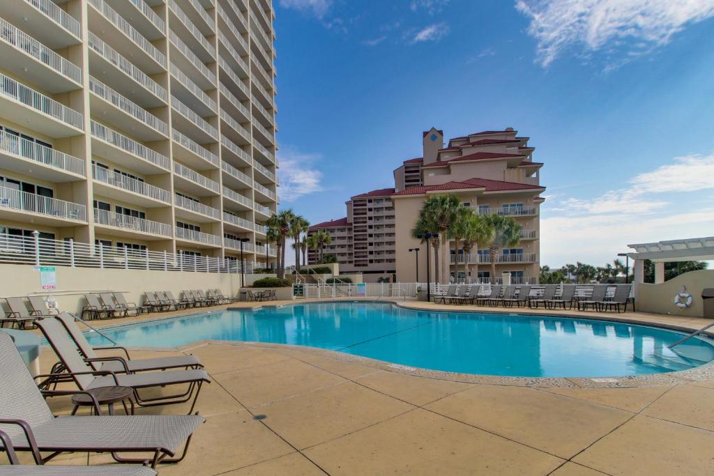 a swimming pool with chairs and a building at TOPS'L Tides I in Destin