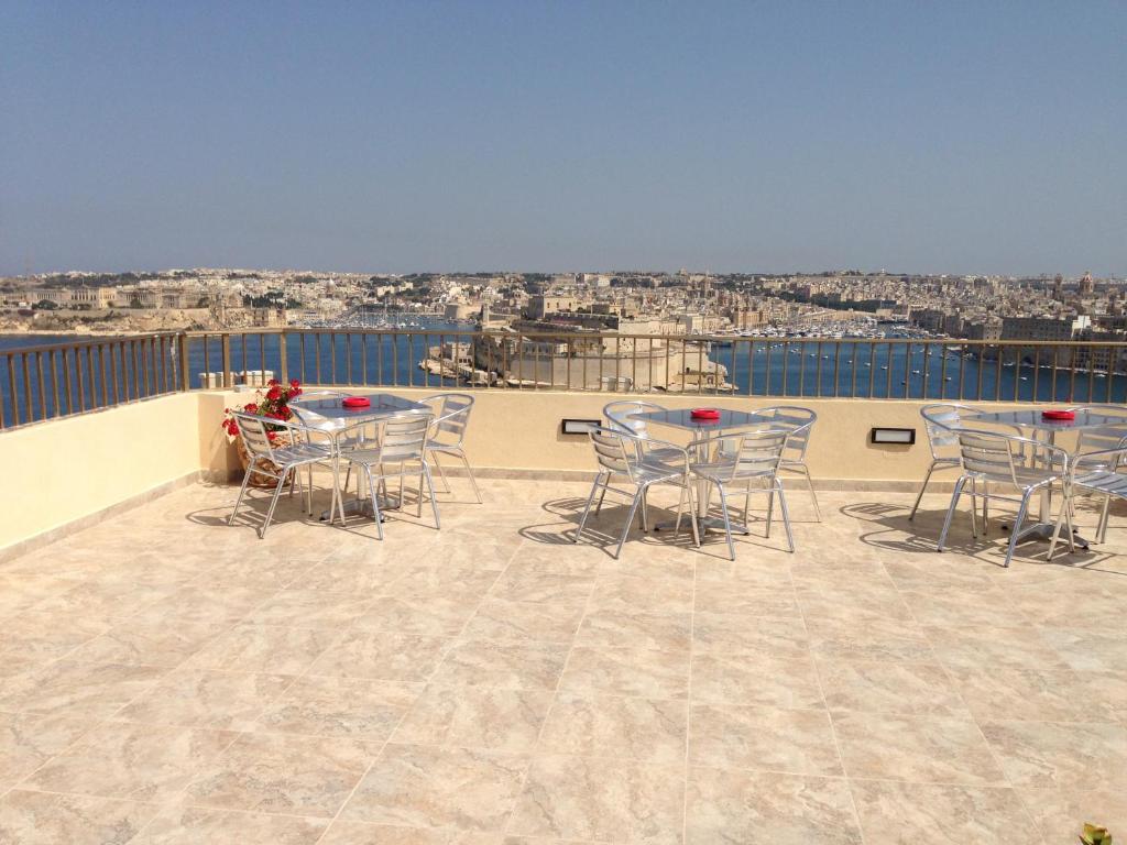 eine Terrasse mit Tischen und Stühlen auf dem Dach in der Unterkunft Grand Harbour Hotel in Valletta