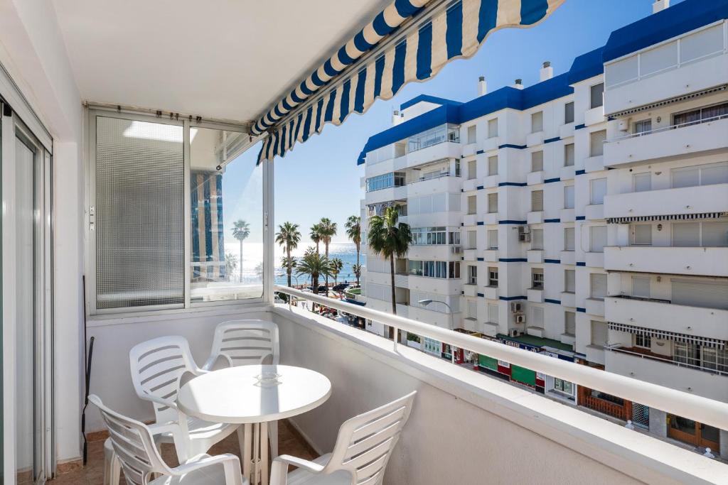ベナルマデナにあるApartamento al lado de la playaのバルコニー(テーブル、椅子付)、大きな窓が備わります。