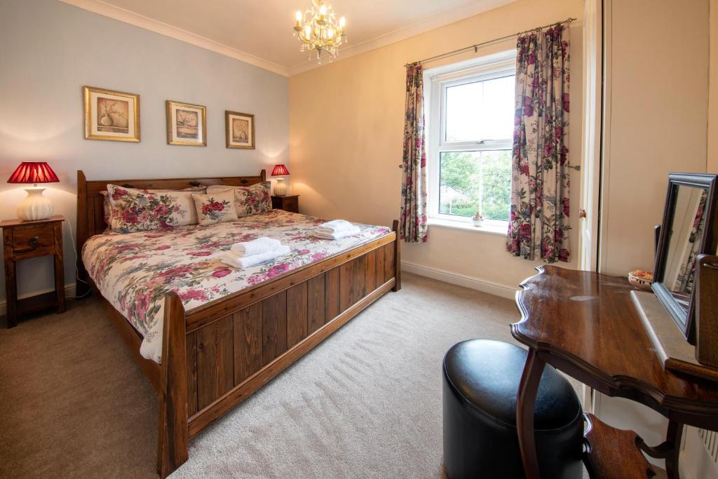 Schlafzimmer mit einem Bett, einem Schreibtisch und einem Fenster in der Unterkunft Harrogate 100 in Harrogate