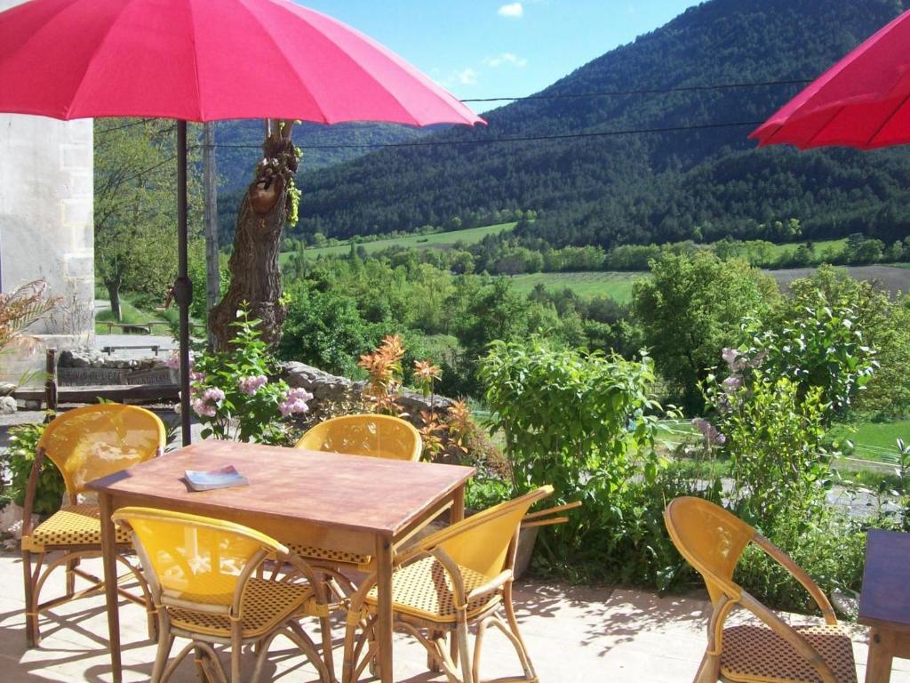 Ponet-et-Saint-AubanにあるLe Vin de l'Etéの黄色い椅子と赤い傘が置かれたテーブル