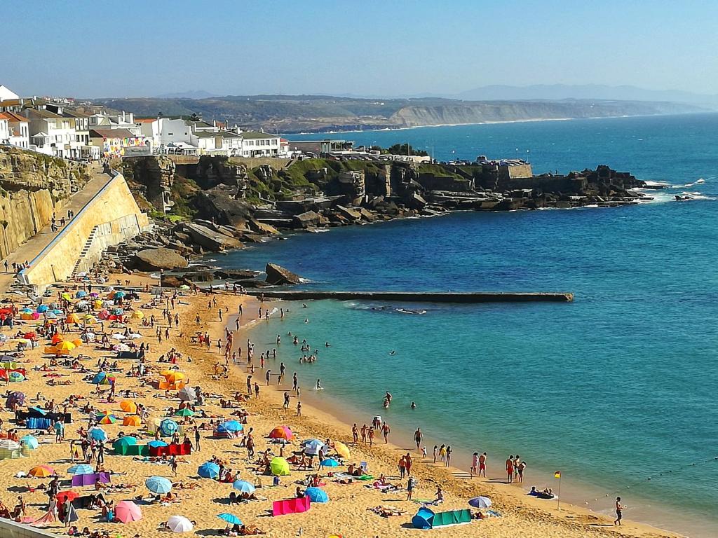 un grupo de personas en una playa con sombrillas en Casa da Avó Isaura - Ericeira, en Ericeira