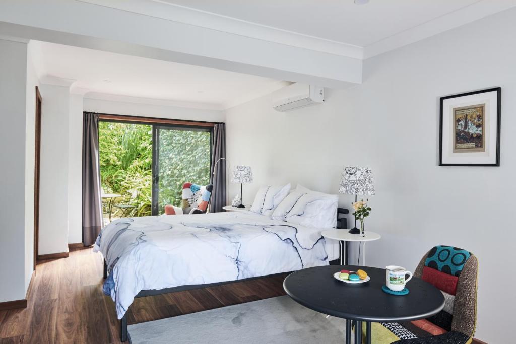 a white bedroom with a large bed and a table at Mountain Sojourn - Tranquil Kurrajong Getaway in Kurrajong