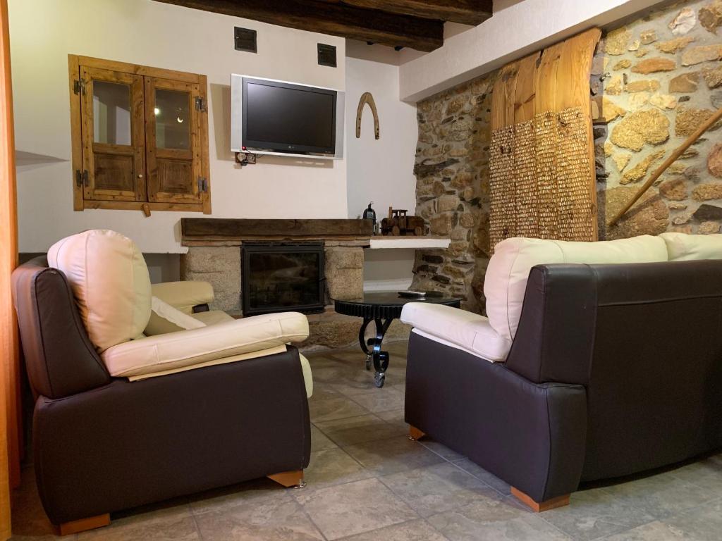 a living room with two chairs and a fireplace at Casa Rural La Vertedera III in Villar de Ciervo