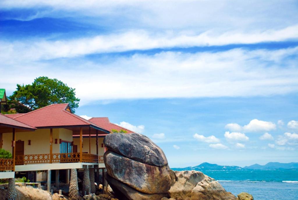 a house with a large rock in front of it at Rin Beach Resort in Haad Rin