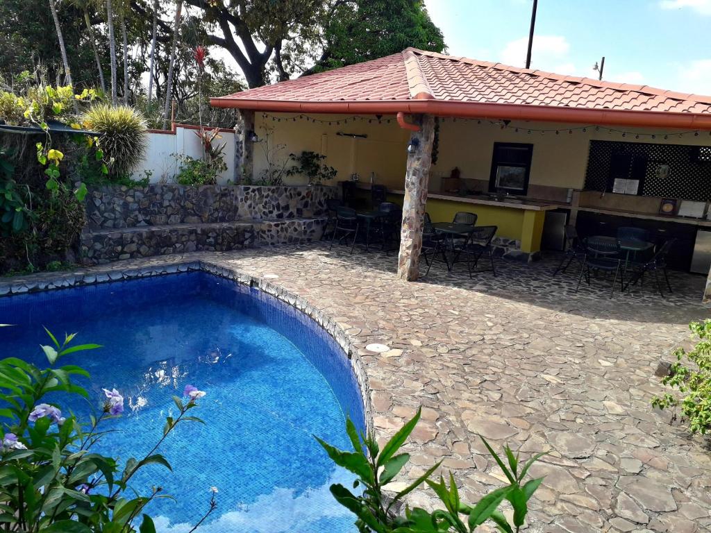 a swimming pool in front of a house at Dos Palmas Studio Apartments in Alajuela