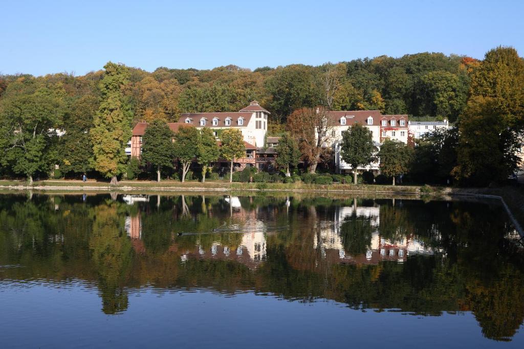 uma vista para um lago com casas e árvores em Les Etangs de Corot em Ville-dʼAvray