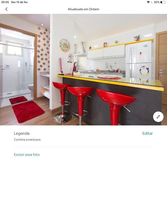 a kitchen with a counter and red stools at Amora Três in São Paulo