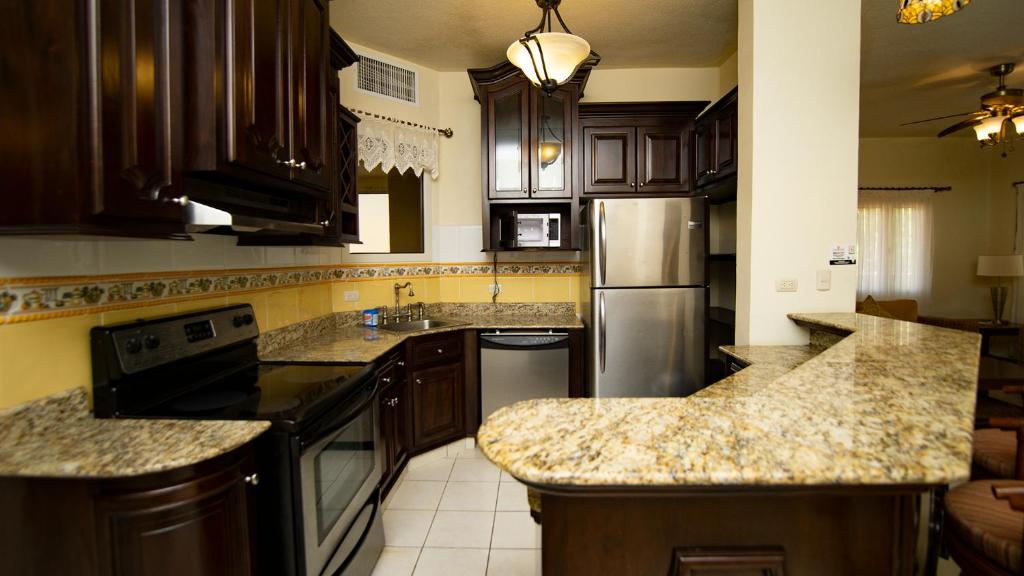 a kitchen with wooden cabinets and granite counter tops at La Ensenada Beach Resort in Tela