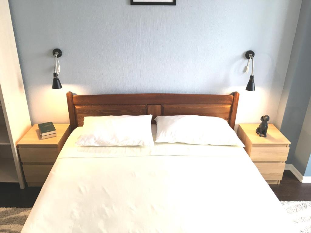 a bedroom with a bed with white sheets and two lamps at Blue Room Homestay in Chişinău