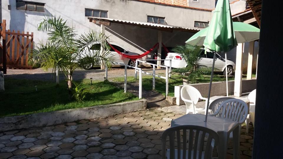 een patio met een tafel en een groene parasol en stoelen bij CHACARA NOSSA SENHORA DAS DORES in Cachoeira Paulista