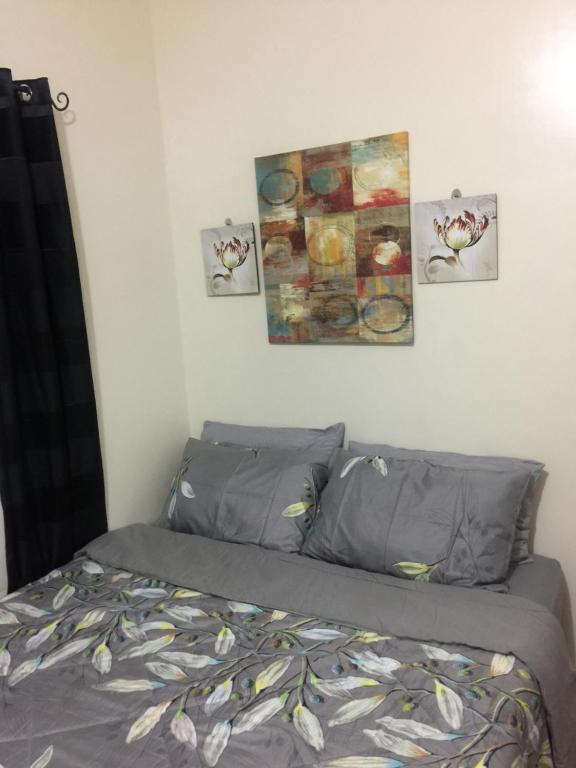 ESTILO APARTMENT 2-storey في Loculan: سرير في غرفة نوم مع ثلاث صور على الحائط