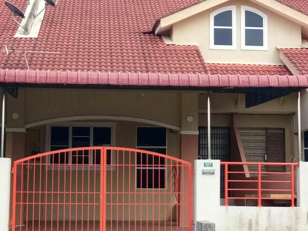 uma casa com um portão vermelho em frente em Homestay Mama Razzin em Kuala Kangsar