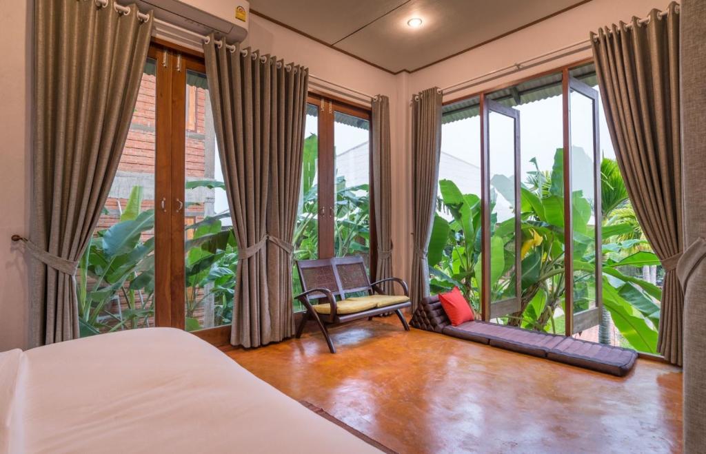 a bedroom with a bed and large windows at BaanSuk Sukhothai Resort in Sukhothai