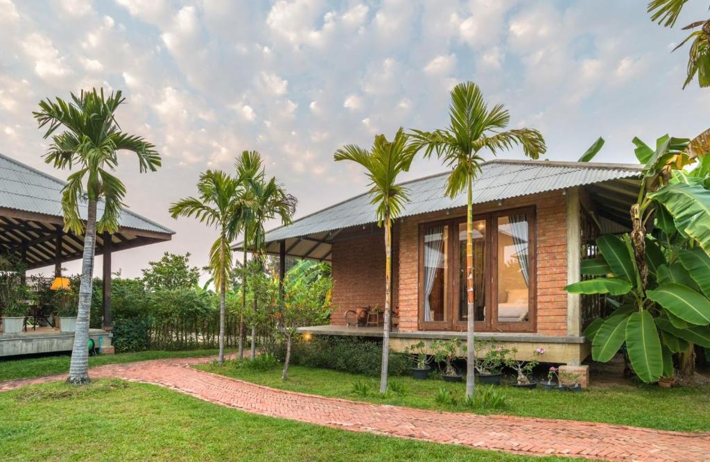 a house with palm trees in front of it at BaanSuk Sukhothai Resort in Sukhothai