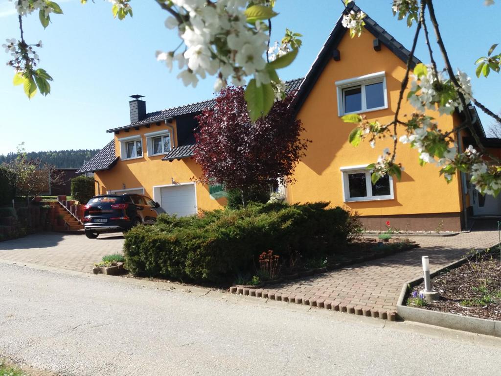 une maison jaune avec une voiture garée dans l'allée dans l'établissement Ferienwohnung Isabella, à Crostau